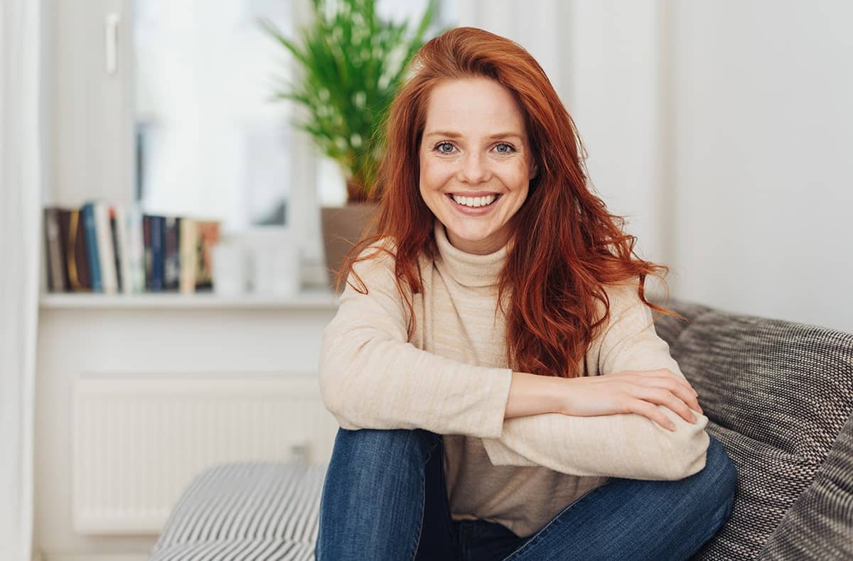 smiling red haired woman relaxing on her couch