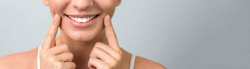 up close image of woman smiling and pointing at mouth