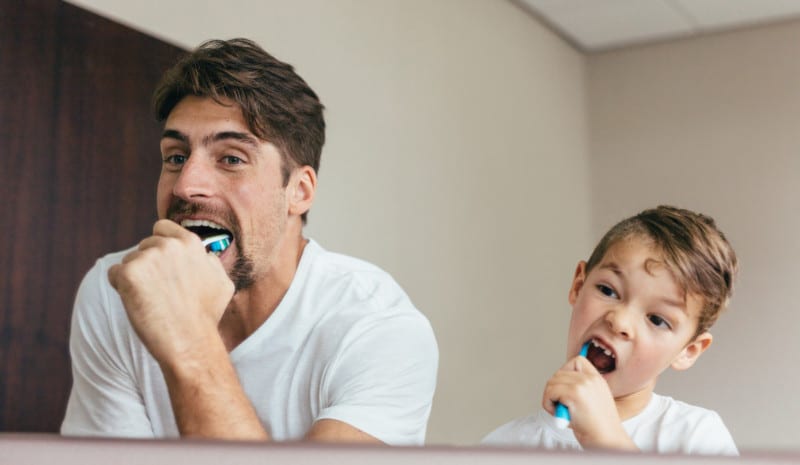 Father and son brushing teeth in bathroom Father and son brushing teeth in bathroom