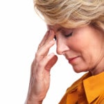 Middle aged woman placing hand on forehead with a headache