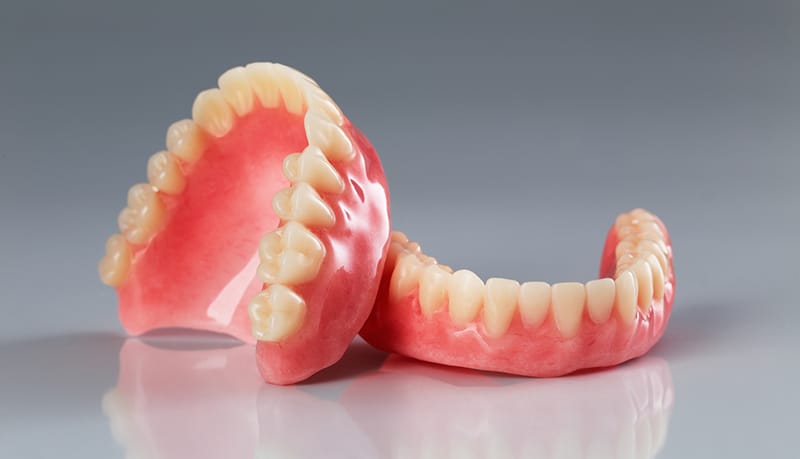 A set of dentures on a shiny gray background