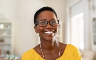 woman with large eye glasses showing off her bright white smile
