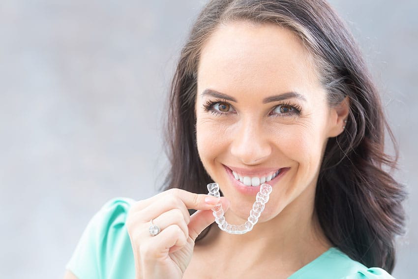 smiling woman shows off her Invisalign clear braces