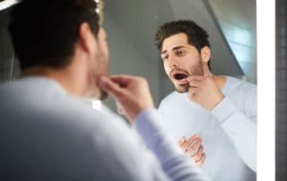 young adult man looking at his teeth in the mirror