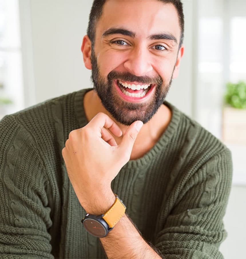Man with short brown beard wearing a green sweater, displaying a happy smile
