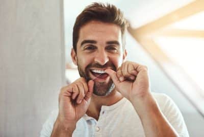 adult man flossing his teeth