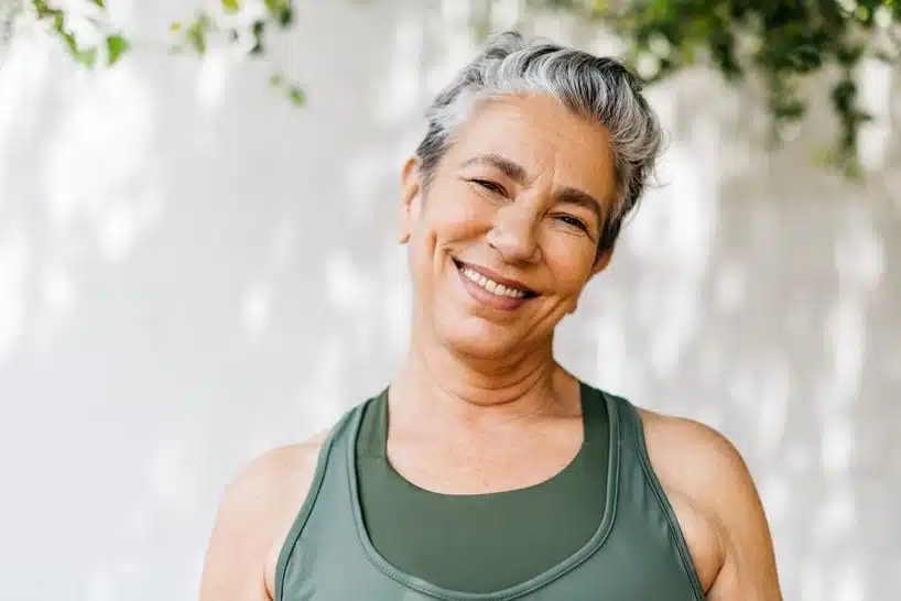 Mature woman with short hair standing outside smiling