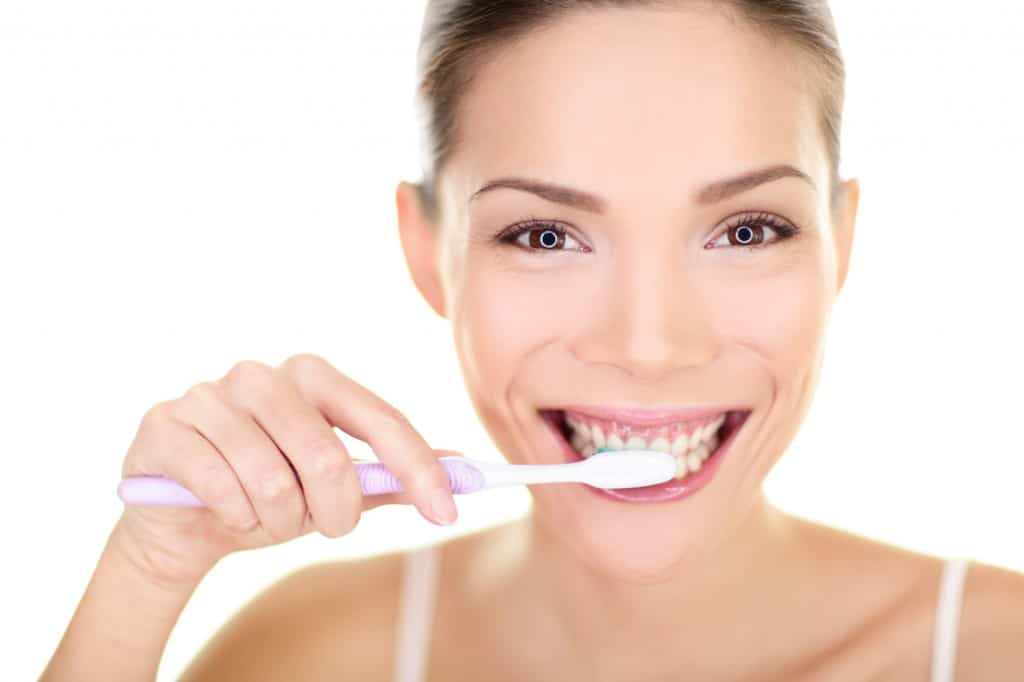Woman brushing teeth holding toothbrush